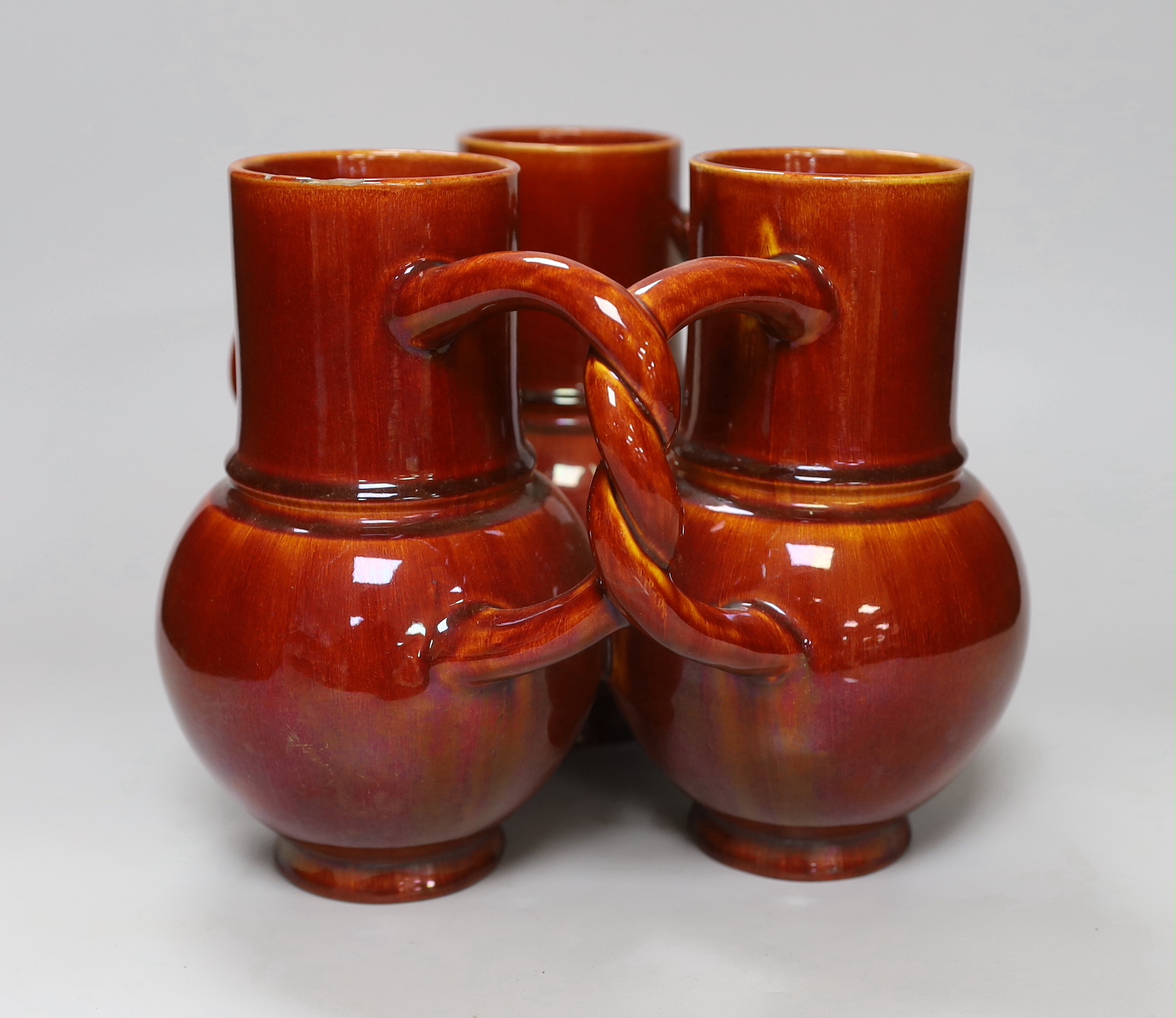 A Burmantofts Pottery three section fuddling cup with interwoven handles in dark burnt orange, stamped with marks to base, height 21cm